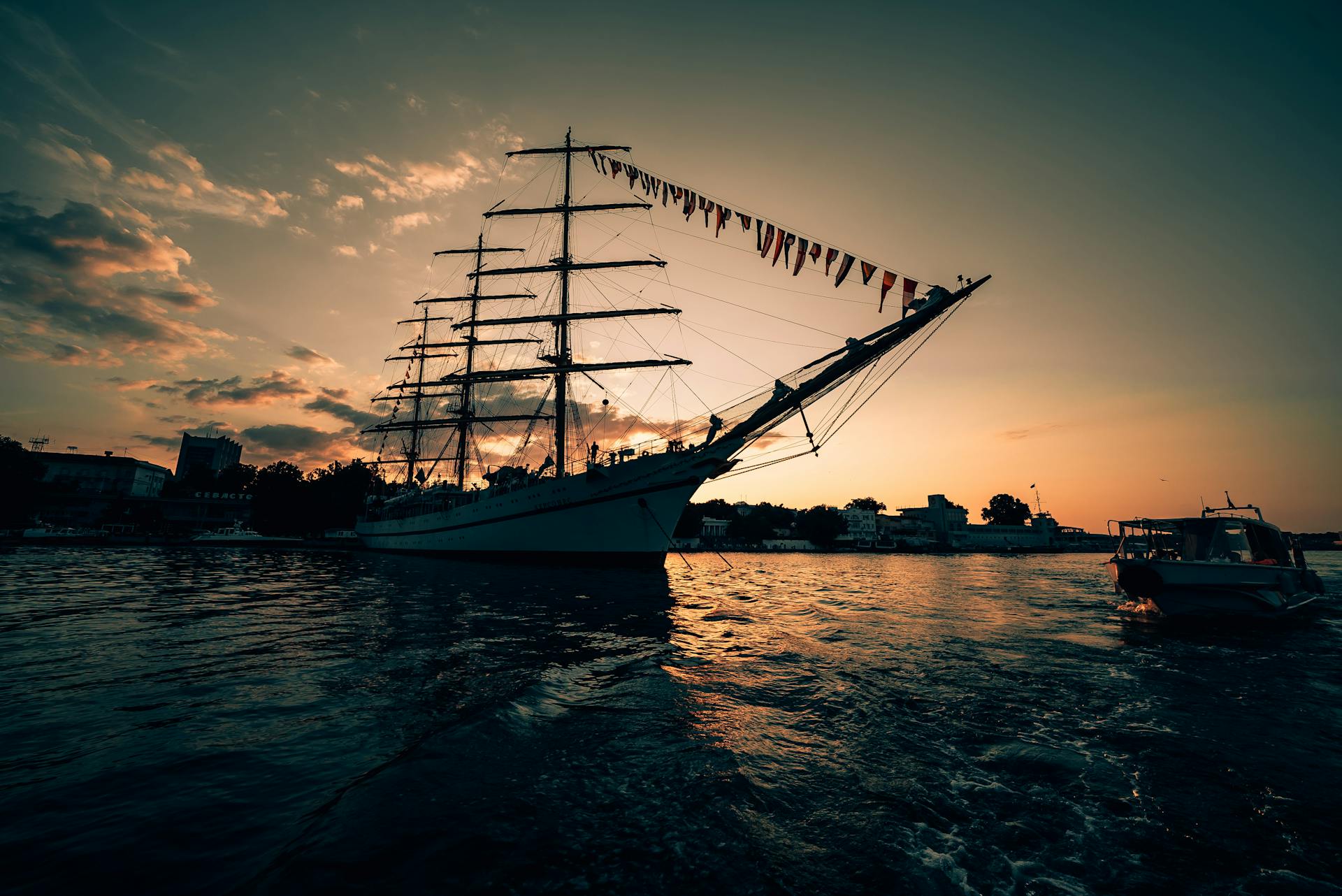 Serene view of a grand sailboat at sunset in Sevastopol harbor, reflecting on water.