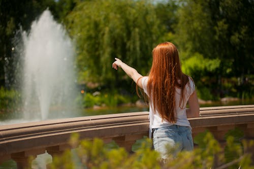 噴水のある水域の前に立っている女性の浅い焦点の写真