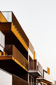 Close-up of a modern building facade featuring metal balconies and concrete elements against a clear sky.