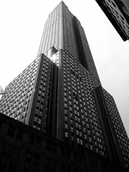 Black and white photo of the Empire State Building shot from a low angle in New York City.