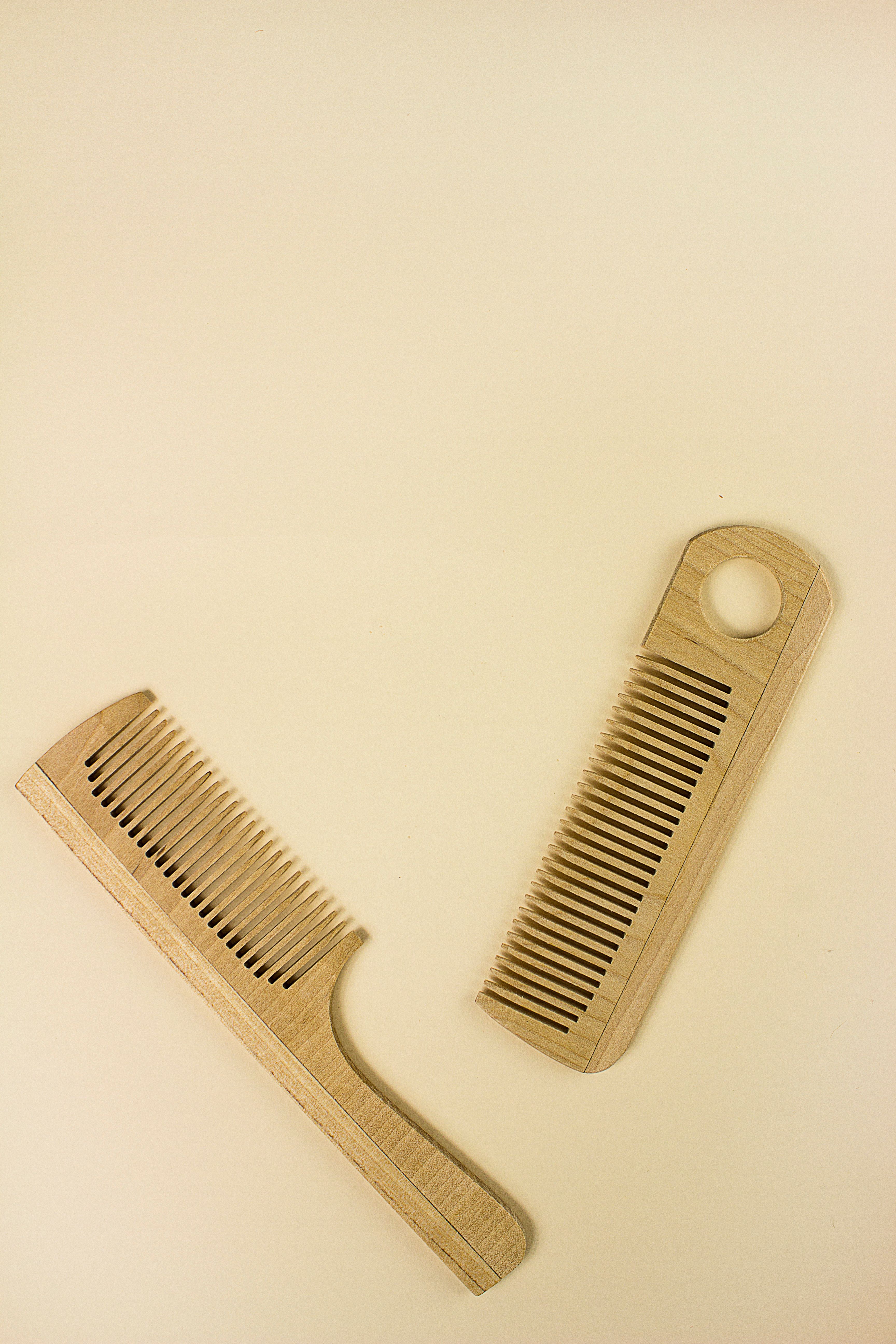 Two wooden combs arranged on a neutral background, ideal for natural hair care themes.