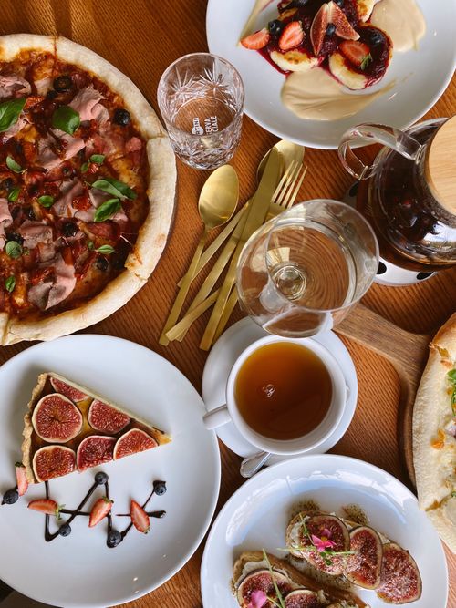 Free A delectable spread featuring pizza, fig tart, and various desserts on a wooden table. Stock Photo