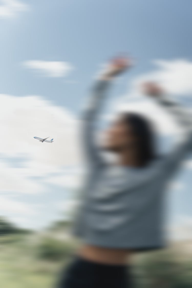 An Airplane In The Sky Behind A Woman