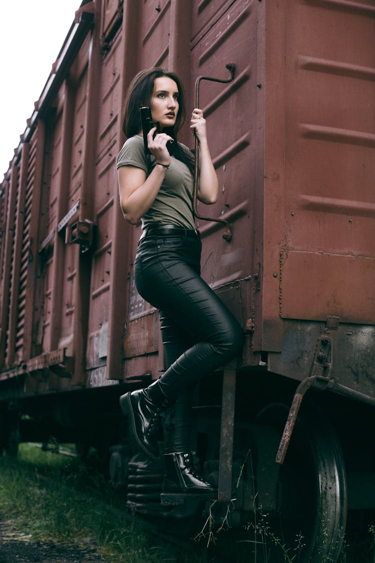 A Beautiful Woman Hanging On A Cargo Train Holding A Gun