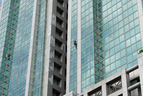 A Person Cleaning Windows of a Building Hanging on a Rope