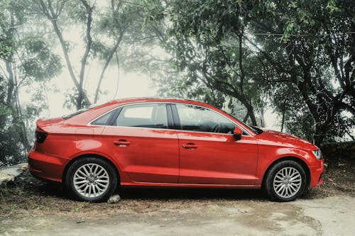 Red Sedan Near Green Trees during Day Time