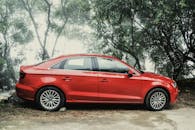 雾蒙蒙的日子里，一辆充满活力的红色轿车优雅地停在郁郁葱葱的绿化中