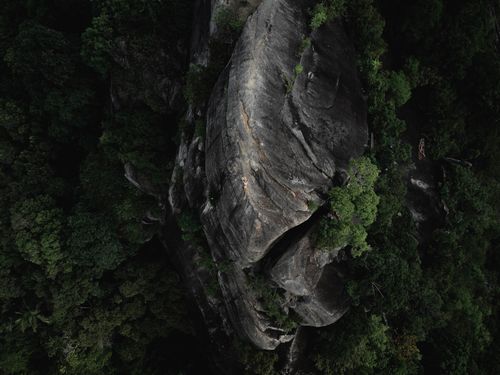 Free Drone shot capturing a stunning rock formation surrounded by lush forest in Thailand. Stock Photo