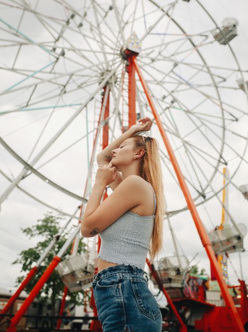 Free A young woman poses in front of a Ferris wheel at an amusement park in Des Moines, Iowa. Stock Photo