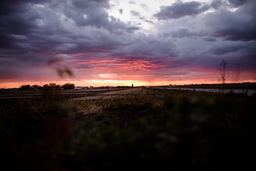 Vivid sunset over rural fields with dramatic clouds and vibrant colors.