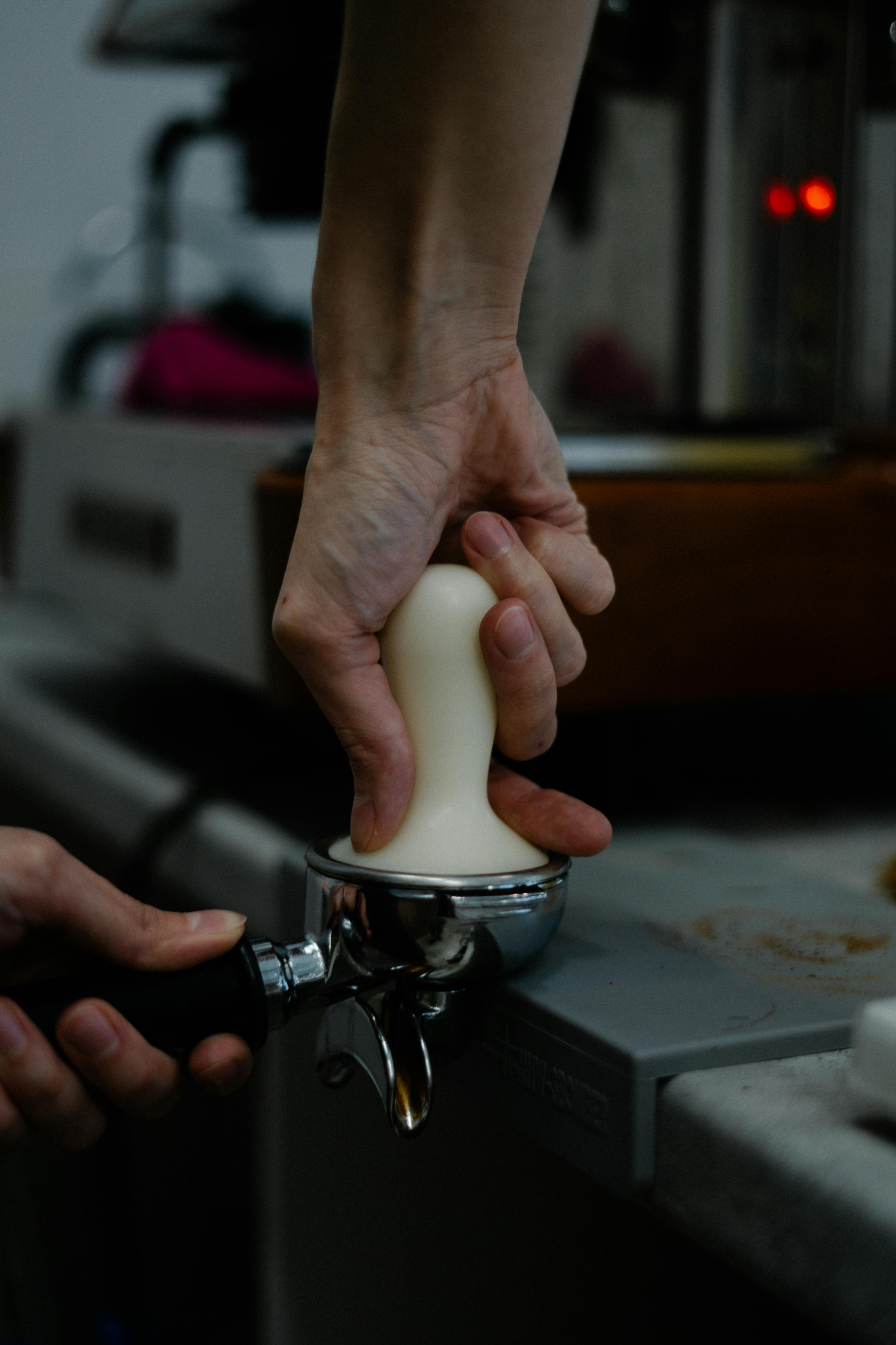 a person pressing coffee on a portafilter