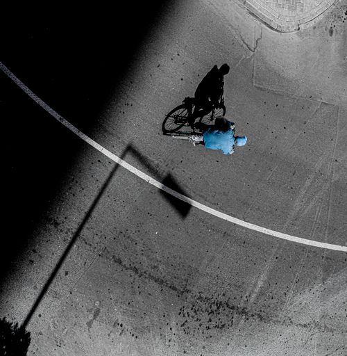 Free Aerial view capturing a cyclist casting a shadow on an urban road at day in Dubai, highlighting contrast and light play. Stock Photo