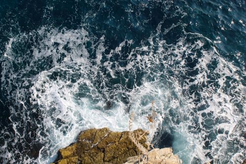 Free Stunning drone shot capturing the waves crashing against rocky shores along the Italian coastline. Stock Photo
