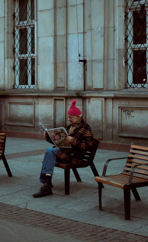 Man Sitting on the Street Reading a Newspaper