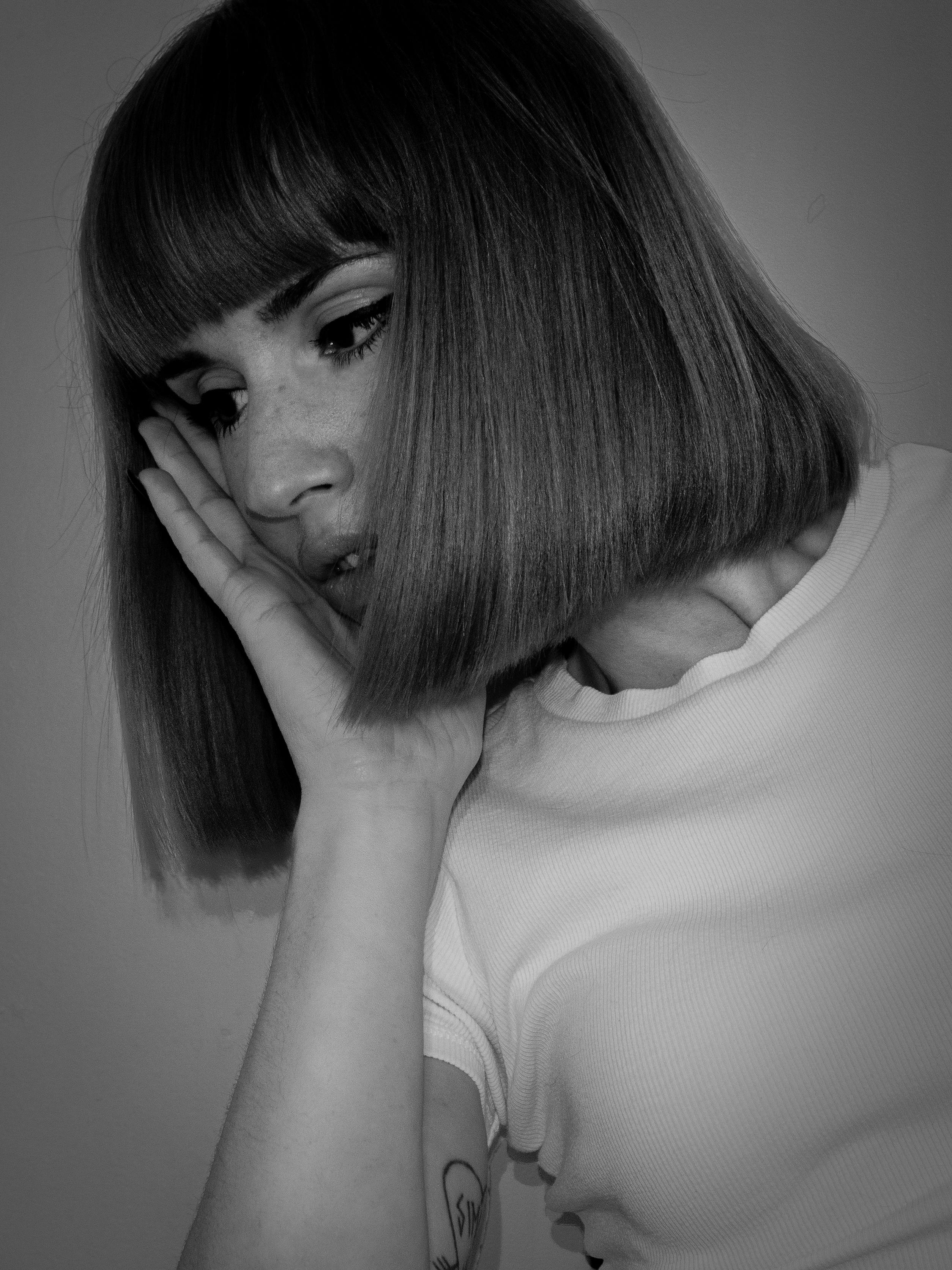 Elegant monochrome portrait of a woman with short hair and bangs, posing thoughtfully.