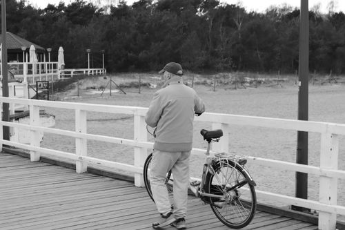 Free A serene monochrome capture of a man with a bicycle on Gdańsk pier. Stock Photo