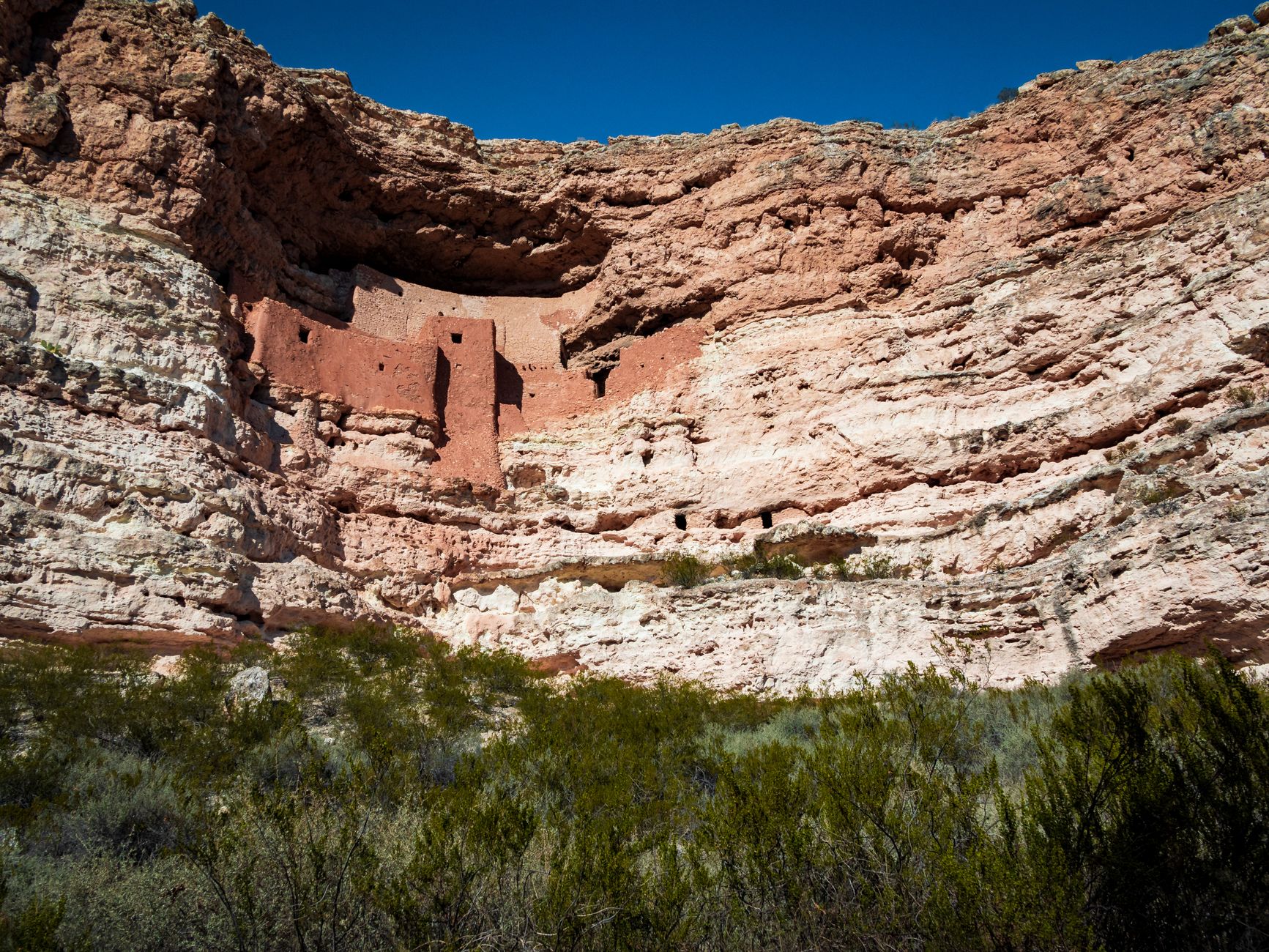 Explore the ancient Montezuma Castle nestled in the red cliffs of Arizona's desert landscape.