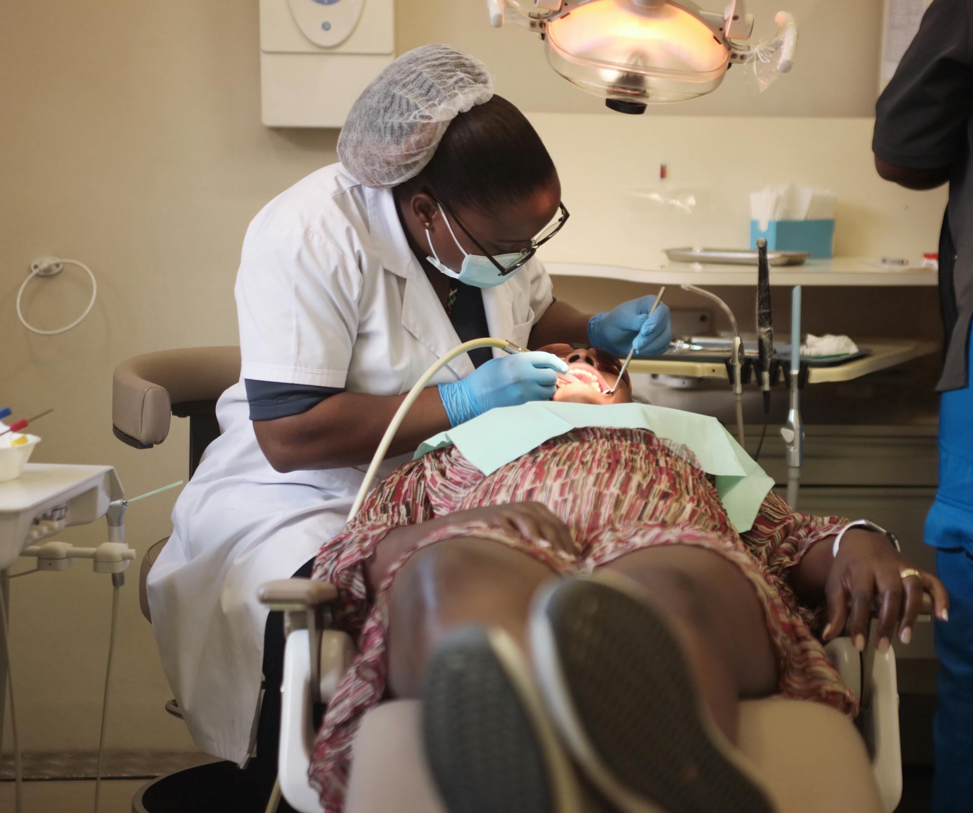 A dentist wearing protective gear performs a procedure on a patient in a Zimbabwe clinic.