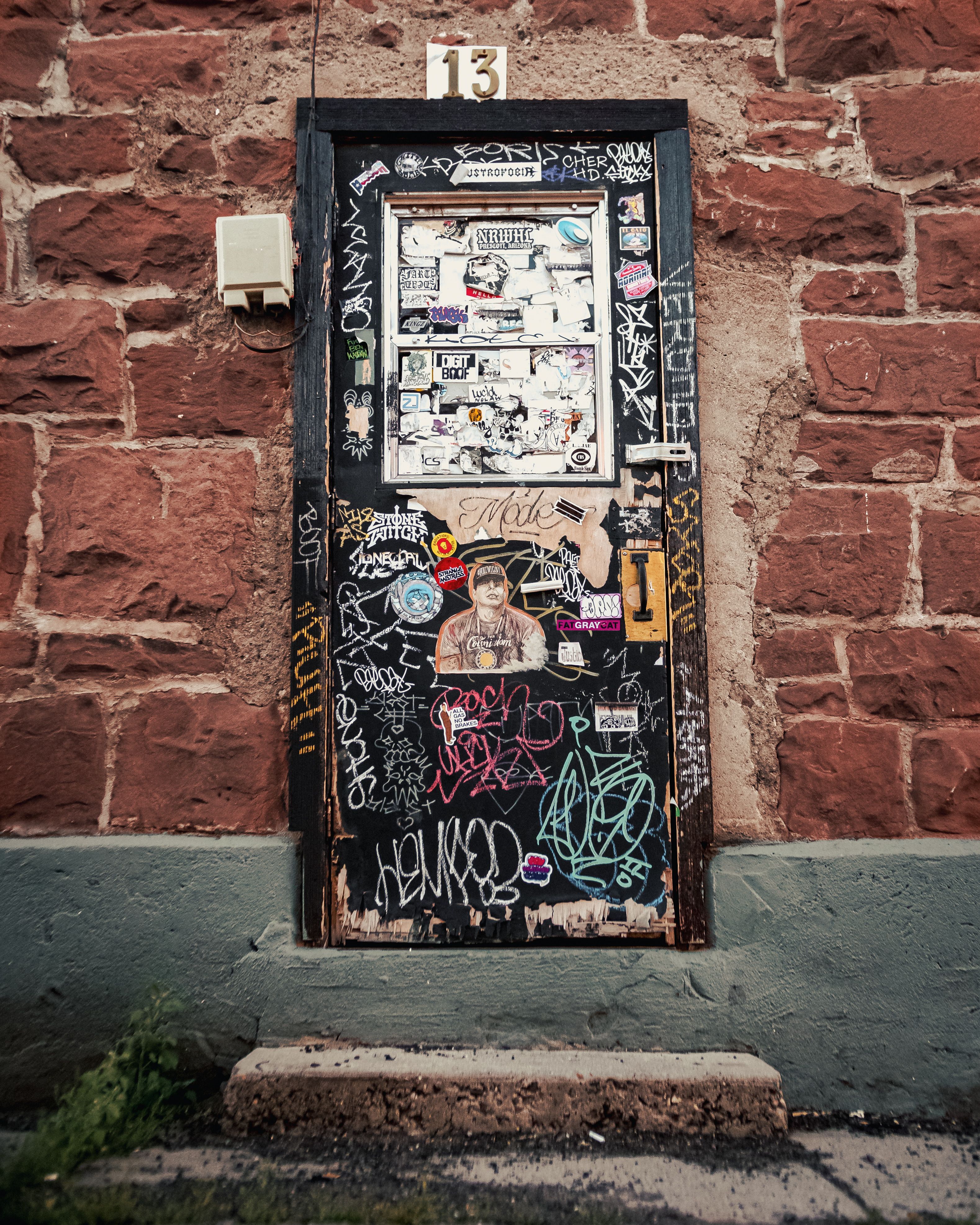 A vandalized wooden door with graffiti on a brick wall in Flagstaff, Arizona.