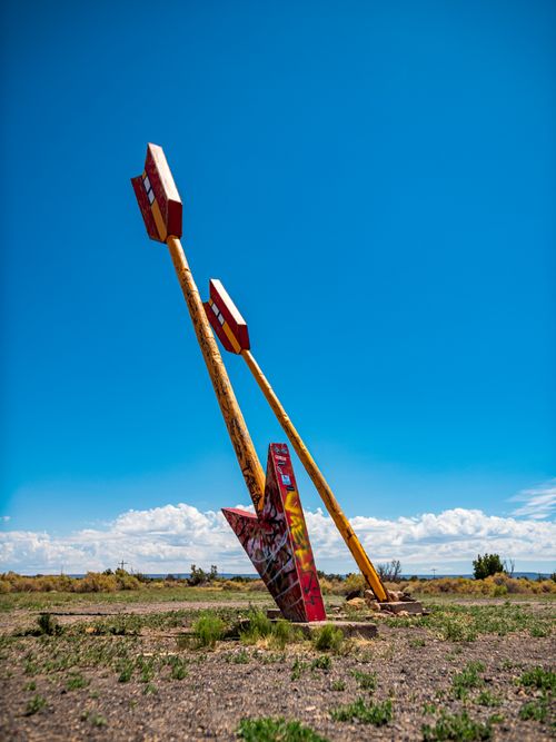 Free Leaning arrows sculpture in the Arizona desert under a vibrant blue sky. Stock Photo