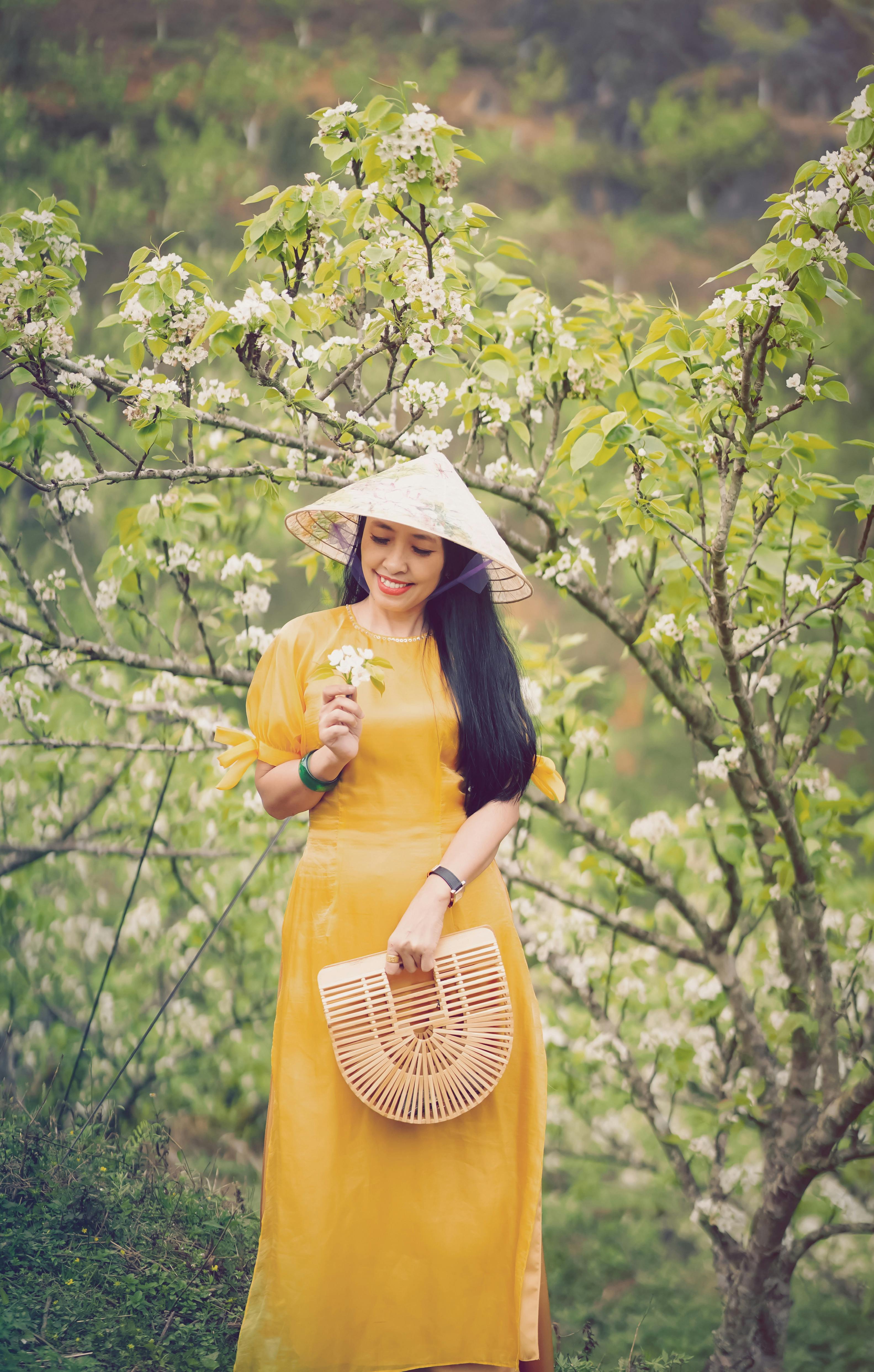 a pretty woman in ao dai looking at flowers