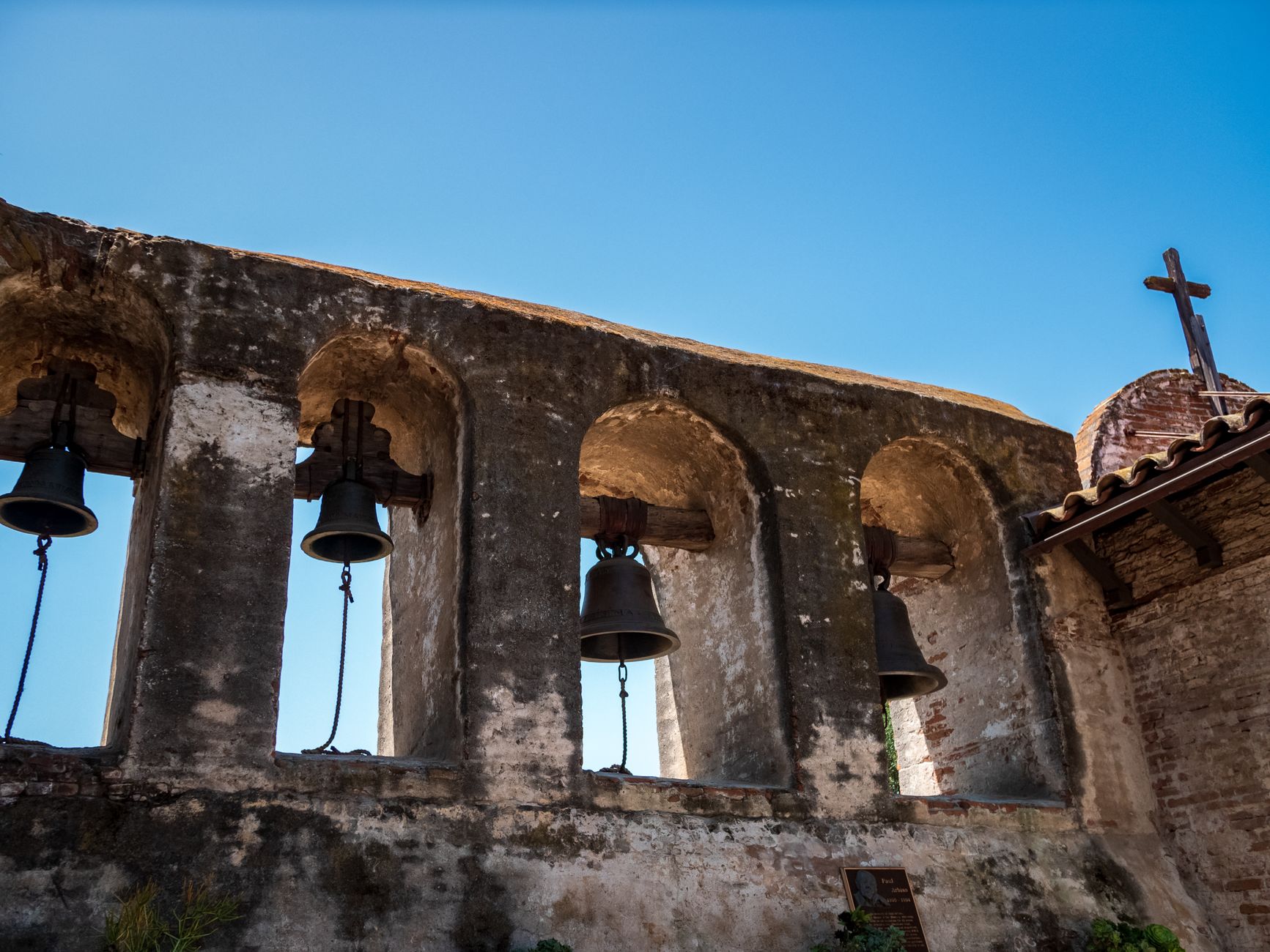 Low-angle view of the iconic bells at Mission San Juan Capistrano against a clear blue sky.