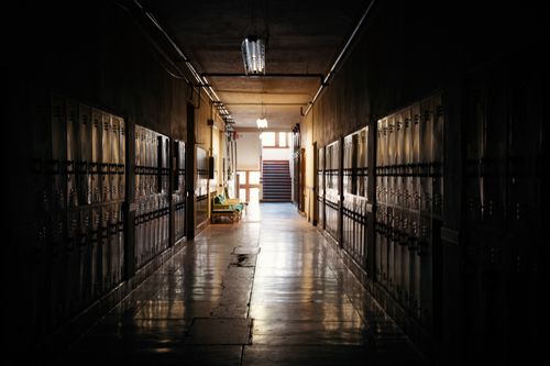 Free A dark and moody school hallway with lockers and a distant light source. Stock Photo