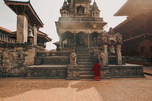 Woman Wearing Red Traditional Gown Standing by an Ancient Temple