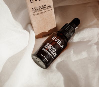 Chilean rose hip oil bottle on white fabric with elegant natural lighting for premium skincare product promotion.