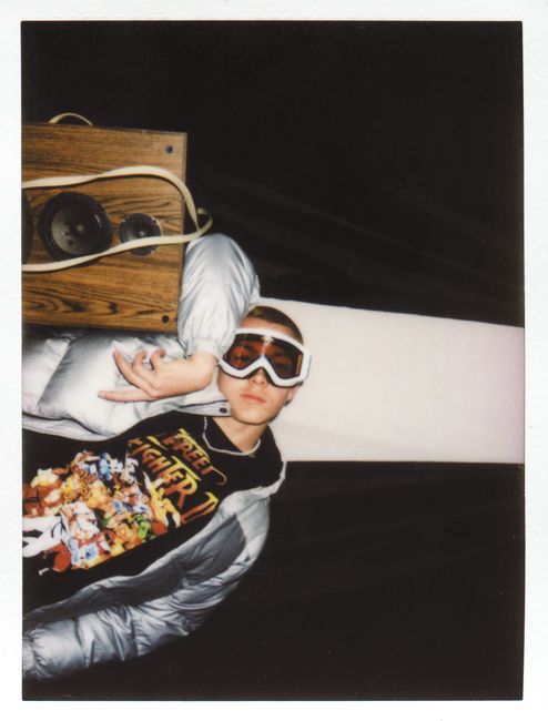 Young adult wearing ski goggles, lying next to a wooden vintage speaker board, creating a retro vibe.
