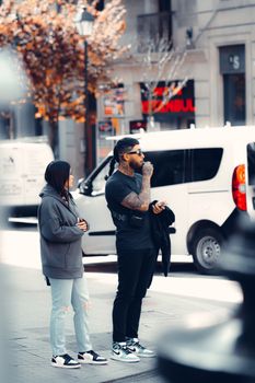Two stylish adults in urban attire standing on a city street with a modern vibe.