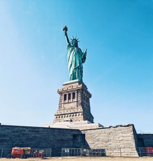 Free Iconic Statue of Liberty with clear blue sky in New York City, a symbol of freedom. Stock Photo