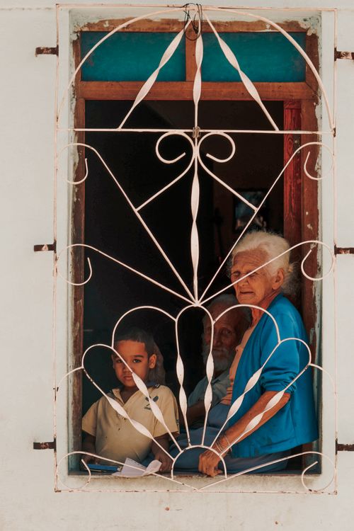 Free A scene of a family looking out from an iron-barred window, capturing generational unity in a warm, intimate setting. Stock Photo