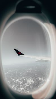 Scenic aerial view from airplane window featuring a wing and distant landscape below.