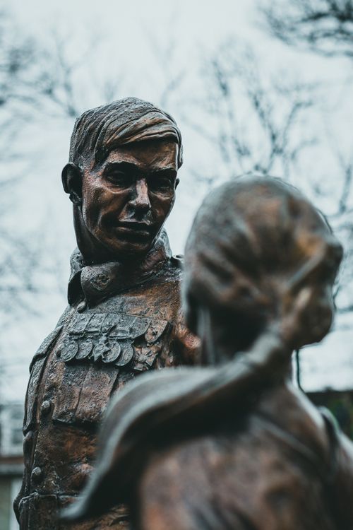 Free Bronze statues of a soldier and a woman in an outdoor setting with a moody atmosphere. Stock Photo