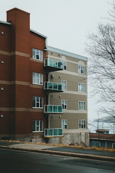 Urban residential building with glass balconies on a cloudy day, showcasing modern architecture.