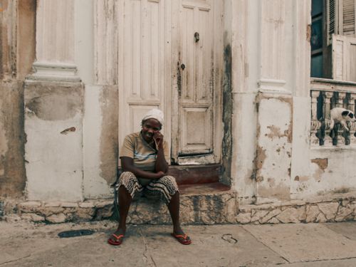 Free A smiling African woman sits by an old doorway, exuding warmth and authenticity. Stock Photo