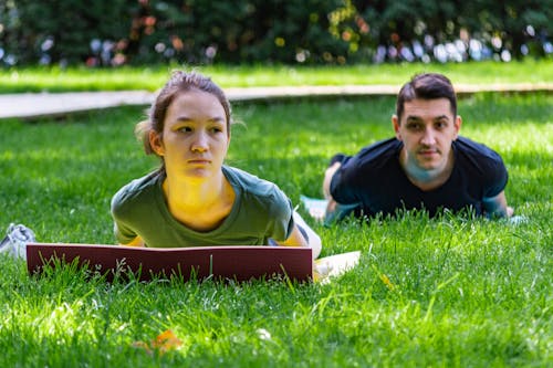 Man and Woman Lying Down on Yoga Mat on Grass Field 