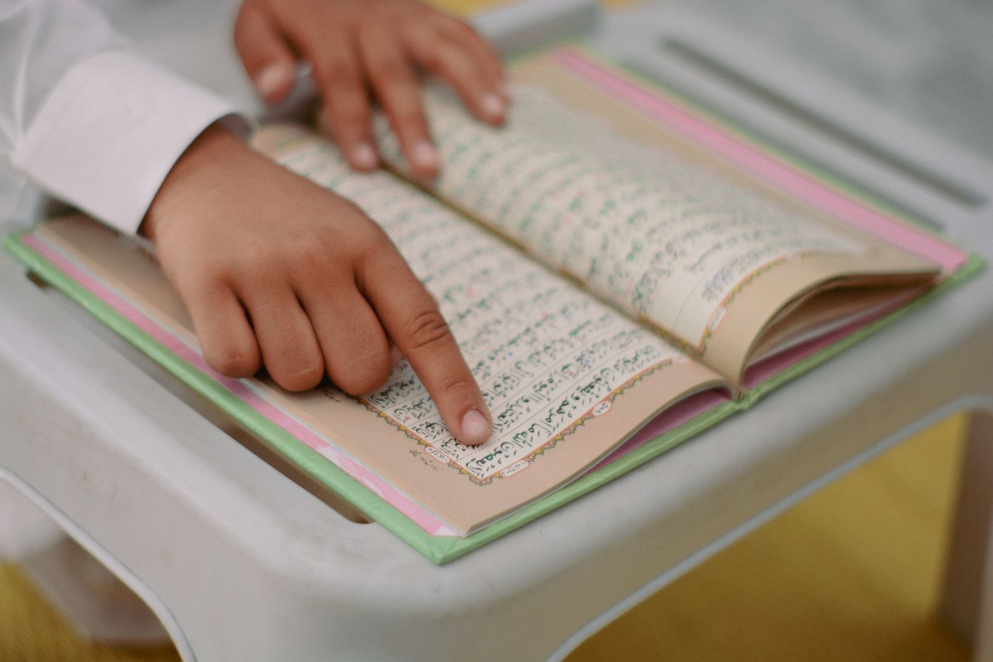 A child following Quran text carefully with a finger