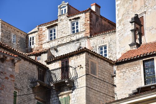 Free Charming rustic stone buildings with balconies and red roofs on a sunny day, showcasing European architecture. Stock Photo