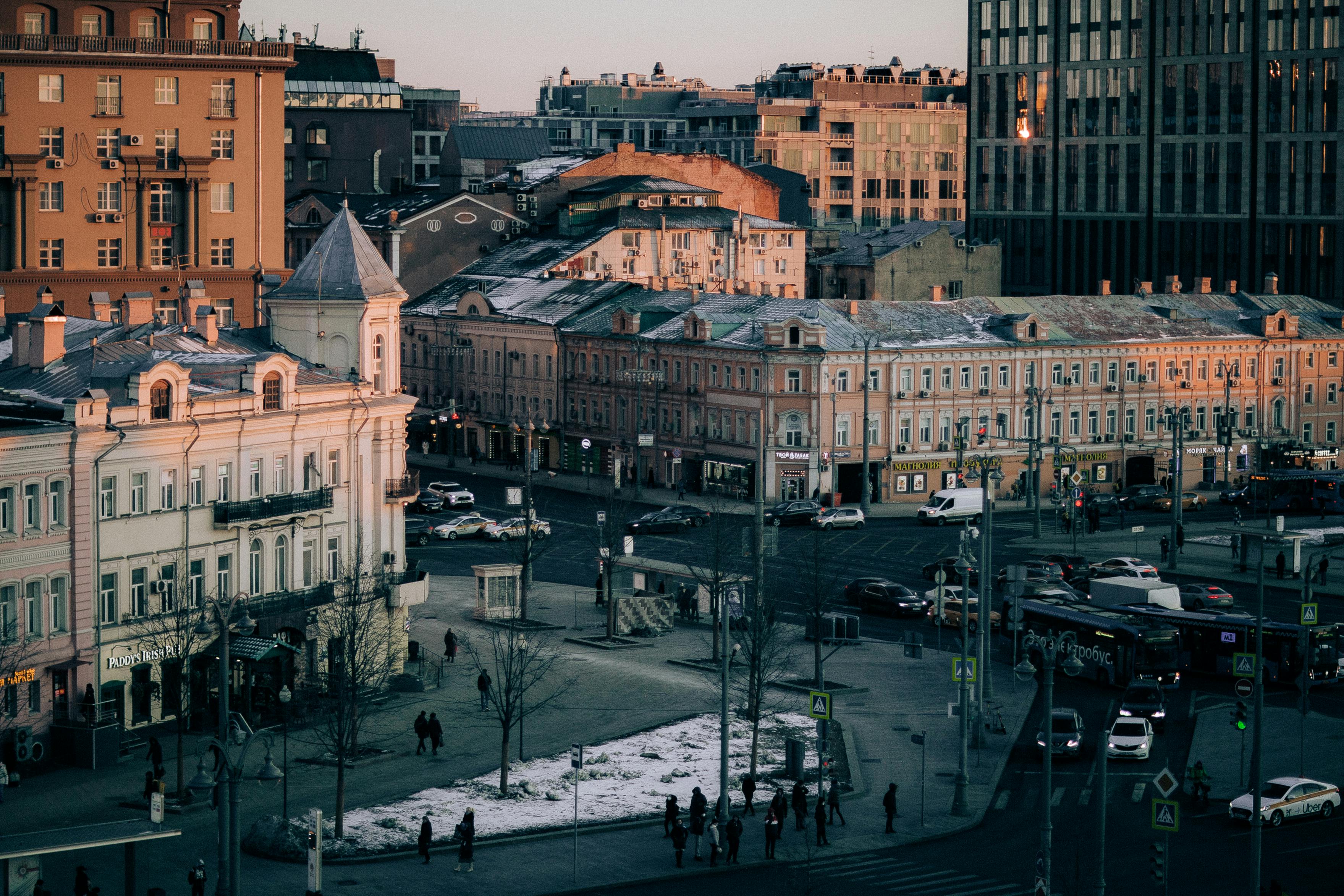 Free A bustling city street lined with historic and modern buildings at dusk. Stock Photo