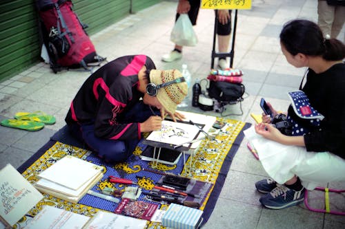 Man Sitting on a Pavement and Creating Art 