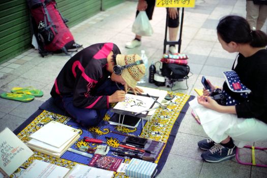 Artist painting on city street with onlookers, showcasing vibrant urban culture.