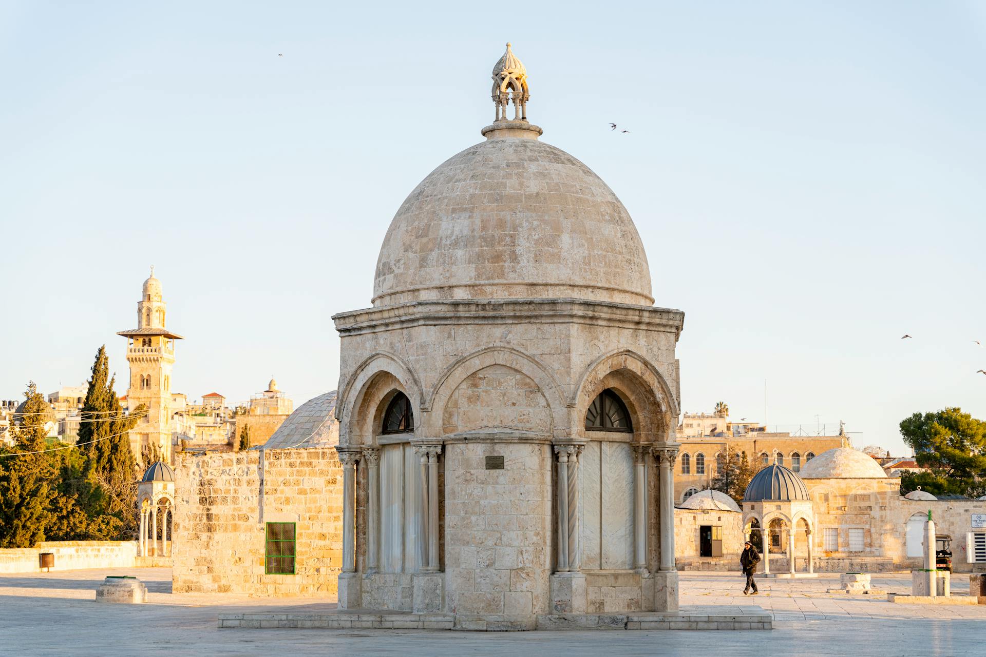 View of historic dome architecture in Jerusalem at sunset with nearby landmarks.