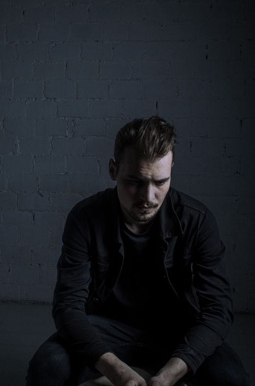 Free A moody portrait of a man in dark attire, seated indoors. Perfect for emotional themes. Stock Photo