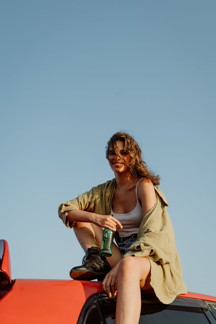 A Woman Sitting On Top Of A Car