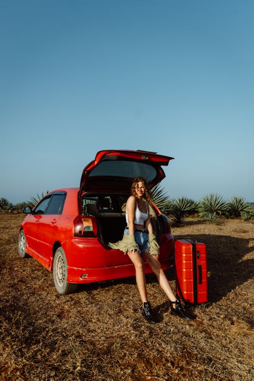 A Woman Sitting at the Trunk of a Car