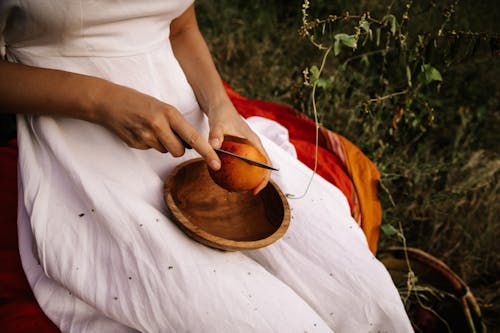 A Woman Cutting a Fruit in Half