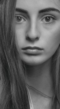 Black and white close-up headshot of a young woman with a serious expression, captured in a studio setting.