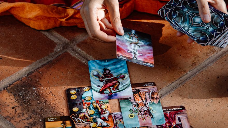 Two hands spreading tarot cards across a table, representing a shared compatibility reading used as a conversation between partners